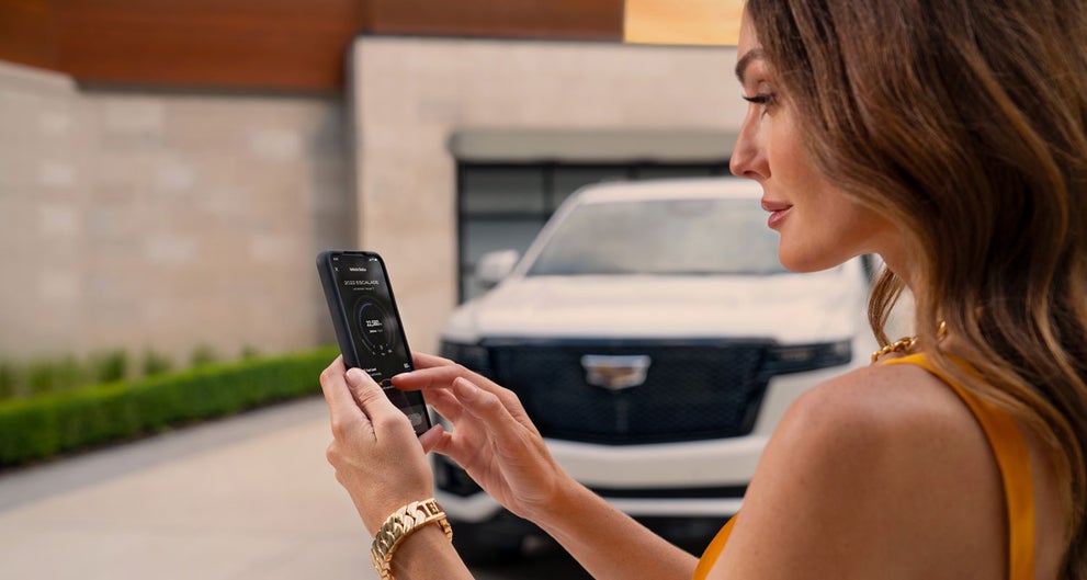 lady checking her mobile with a Cadillac vehicle background | Leachman Cadillac in Bowling Green KY